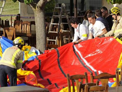 Operarios y bomberos retiran el castillo hinchable.