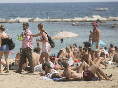 Una agente de la Guardia Urbana de paisano para a un vendedor de mojitos este miércoles en la Barceloneta.