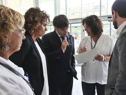 El presidente de la Generalitat, Carles Puigdemont, la ministra de Sanidad, Dolors Montserrat, y el consejero de Salud, Antoni Comín, atienden las indicaciones del personal del hospital de Sant Pau durante su visita a los heridos.