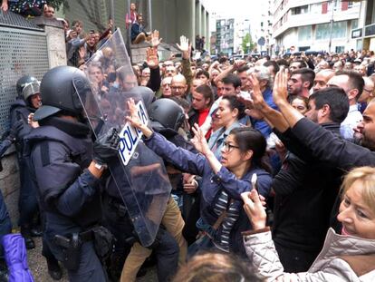 Votantes de un colegio electoral de Girona forcejean con agentes antidisturbios de la Policía Nacional que acudieron a clausurar el centro e incautarse de las urnas.