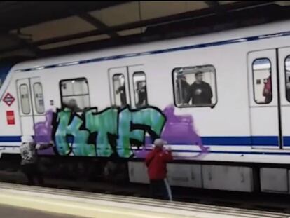 Dos jóvenes pintan un grafiti en un vagón de metro en la parada de Lucero poco antes de ser ahuyentados.