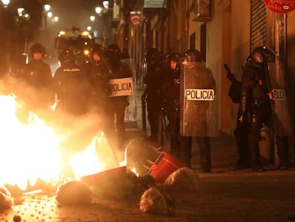 Agentes antidisturbio, frente a varios contenedores que arden en una calle de Lavapiés. En vídeo, enfrentamientos en las calles de Lavapiés.