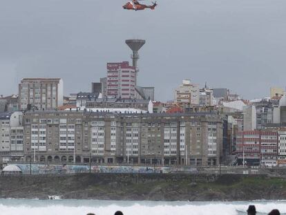 Un helicóptero rastrea la zona de la playa de Orzán, en A Coruña, este viernes.