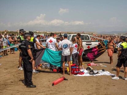 Policías, miembros de Cruz Roja y y bañistas en torno al cadáver de un joven hallado en la playa de la Malvarrosa, en Valencia.