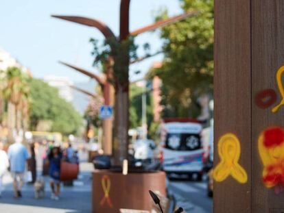 Varias personas pasan ante unos lazos amarillos en el barrio de Sants de Barcelona la semana pasada.