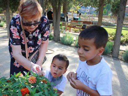 Foto: Unos niños disfrutan de un banco sensorial con su abuela. Vídeo: Reportaje sobre el Jardín Terapéutico de Coslada.