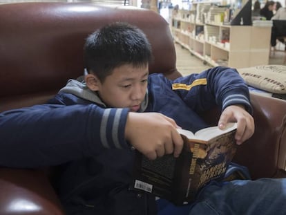 Hao Yu, de 12 años, lee un libro en la librería +Bernat, en Barcelona.