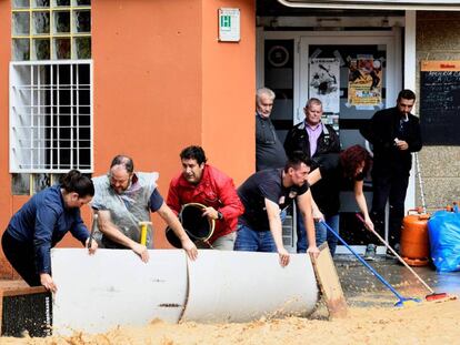 Varios vecinos intentan bloquear el paso del agua en Arganda del Rey (Madrid).