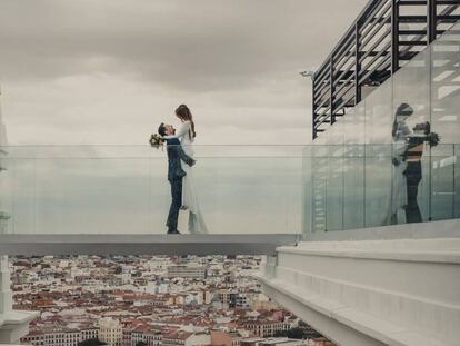 Marta y Javi posan en la pasarela de cristal de la terraza del Edificio España el día de su boda. En vídeo, la pareja recién casada.