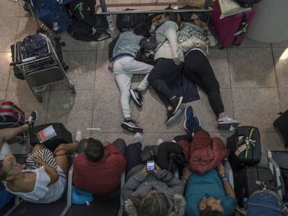 Pasajeros durmiendo en la terminal 1 del aeropuerto de Barcelona. En vídeo, así fueron los choques entre manifestantes y policía en El Prat.