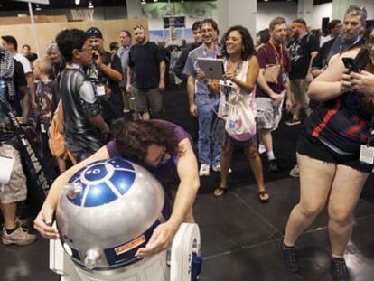 Varios asistentes se toman fotografías con un R2-D2 expuesto en la convención de Anaheim, California.