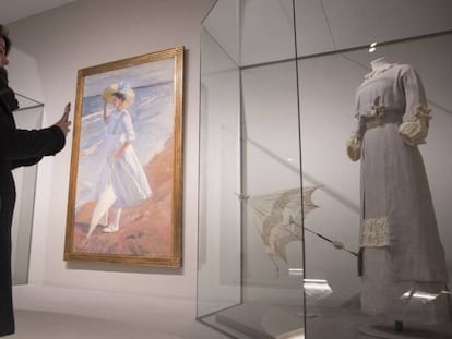 Una visitante fotografía uno de los vestidos de la muestra 'Sorolla y la moda' que se expone junto con el lienzo del pintor 'Elena en la playa' (1909) en el Museo Thyssen de Madrid.