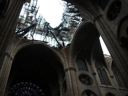 Interior de la catedral de Notre Dame, donde se observa la vidriera del rosetón bajo el techo destrozado por el incendio. En vídeo, cómo trabajaron los bomberos en el interior del templo.