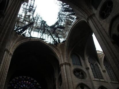 Interior de la catedral de Notre Dame, donde se observa la vidriera del rosetón bajo el techo destrozado por el incendio. En vídeo, cómo trabajaron los bomberos en el interior del templo.