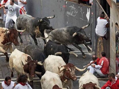 Los miura toman la curva de Estafeta en el último encierro de San Fermín 2019.