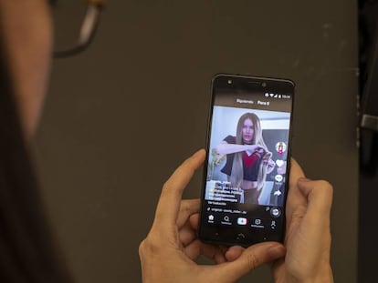 Uma mulher assiste a um vídeo no TikTok. No vídeo, o trailer do app.