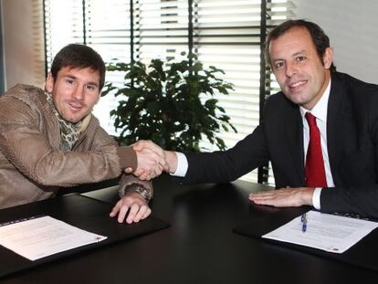 Messi y Rosell se dan la mano tras la firma.