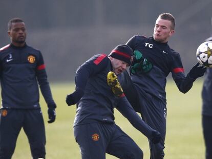 El jugador del Manchester Tom Cleverley da una pata a Rooney, durante el entrenamiento.