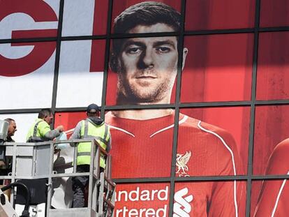 Operarios colocan un mural con el rostro de Gerrard en Anfield