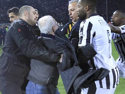 FOTO: Un guardia de seguridad sujeta este domingo a Ivan Savvidis, presidente del PAOK, después de que este saltase al campo con una pistola en la cintura. En vídeo, imágenes de la entrada al campo de Savvidis.