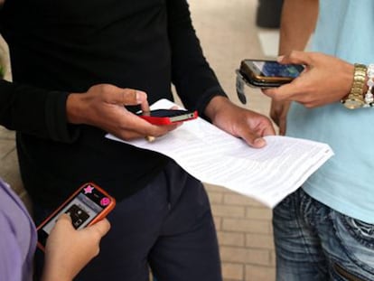 Tres jóvenes usan sus teléfonos móviles.