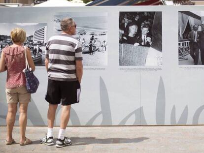Unos turistas observan la exposición "Una mirada al turismo", en Torremolinos.