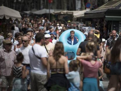 Un turista con flotador y toalla al hombro baja por las Ramblas.