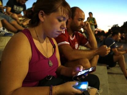 Una jugadora de Pokémon Go en el Parque de El Retiro, en Madrid, usando una batería portátil.