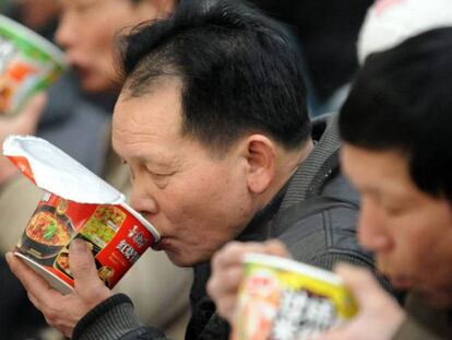 Varios pasajeros comen fideos instantáneos en la estación de tren de Shenyang.