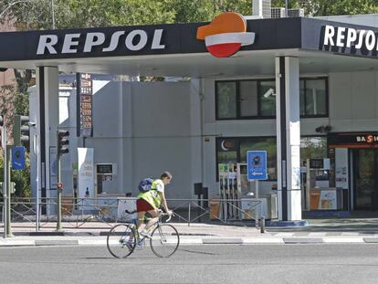 Una ciclista pasa ante una gasolinera de Madrid.