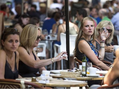 Varios turistas se refrescan en una terraza junto a La Lonja de Valencia.