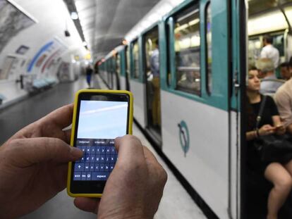 Un hombre sujeta un móvil en el metro de París.