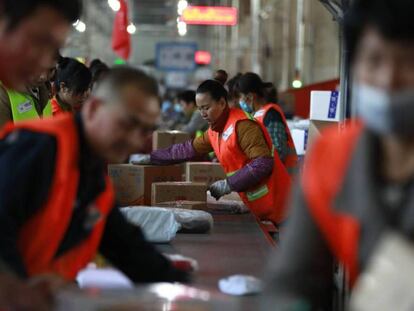 Trabajadores chinos clasifican pedidos de la empresa JD.com en Pekín con motivo del Día del soltero.