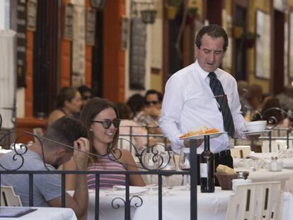 Un camarero atiende una mesa en un restaurante de Ronda (Málaga). En vídeo, declaraciones de Mariano Rajoy.