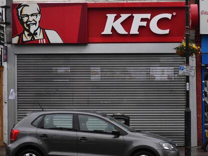 Un peatón camina en Londres este lunes delante de un local de KFC cerrado.