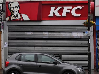 Un peatón camina en Londres este lunes delante de un local de KFC cerrado.