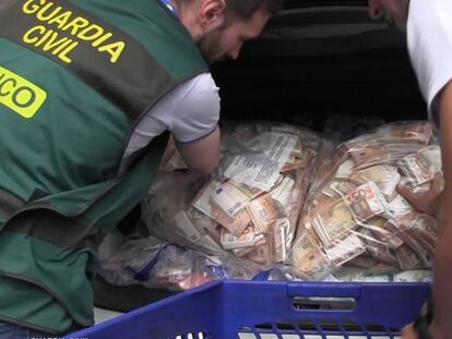 En vídeo: Desmantelada una red dedicada al lavado de dinero (GUARDIA CIVIL) / Foto: Dos agentes de la Guardia Civil colocan sacos con billetes de 50 euros en un coche.