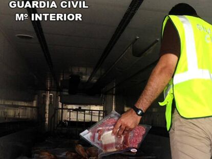 Un guardia civil en el interior del camión donde se encontraron miles de jamones caducados. En vídeo, imágenes de la incautación de 10.700 jamones y embutidos congelados en mal estado de conservación en Fuente Vaqueros (Granada).