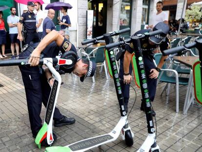 Agentes de la Policía Local de Valencia retiran patinetes eléctricos de Lime en la plaza de la Reina.