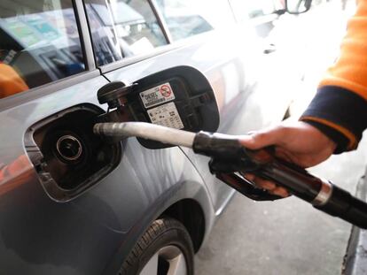 Un empleado de una gasolinera echa combustible a un coche.