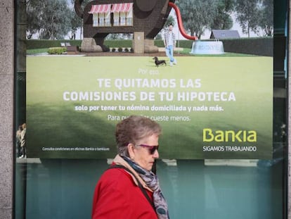 Una mujer pasa ante cartel que publicita hipotecas en una sucursal bancaria. En vídeo, las asociaciones de consumidores califican la sentencia del Supremo de "aberrante".