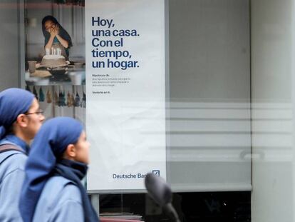 FOTO: Dos religiosas pasan ante un cartel publicitario de una entidad bancaria en Valencia. / VÍDEO: Primer día del real decreto que obliga a la banca a pagar el impuesto hipotecario.