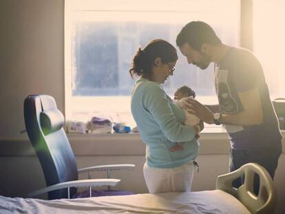 Una pareja mira a su recién nacido. En vídeo, hacienda devolverá también a los padres el IRPF correspondiente al permiso de paternidad.