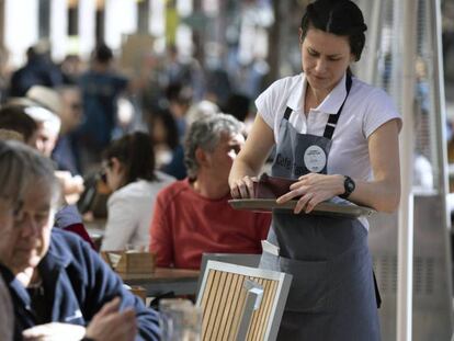 Una camarera en una terraza en la ciudad de Valencia. En vídeo, la ministra de Economía Nadia Calviño valora la EPA.