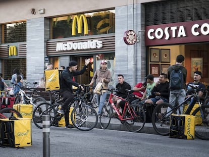 Diversos repartidors esperen davant d'un establiment de menjar ràpid a Barcelona.