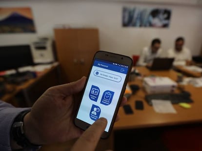 Un usuario muestra una aplicación móvil para fichar en el puesto de trabajo.