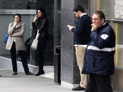 Varias personas fuman durante un descanso de su trabajo en el centro de Madrid. En vídeo, entrevista a Mari Cruz Vicente, secretaria confederal de acción sindical de CC OO.