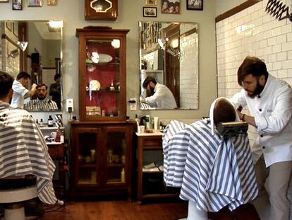 Dos barberos atienden a unos clientes en Malayerba.