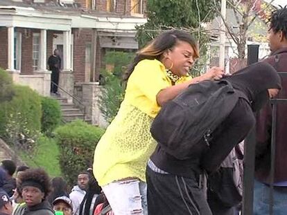 Una madre saca a su hijo de los disturbios de Baltimore