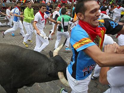 Un toro cornea a un corredor.